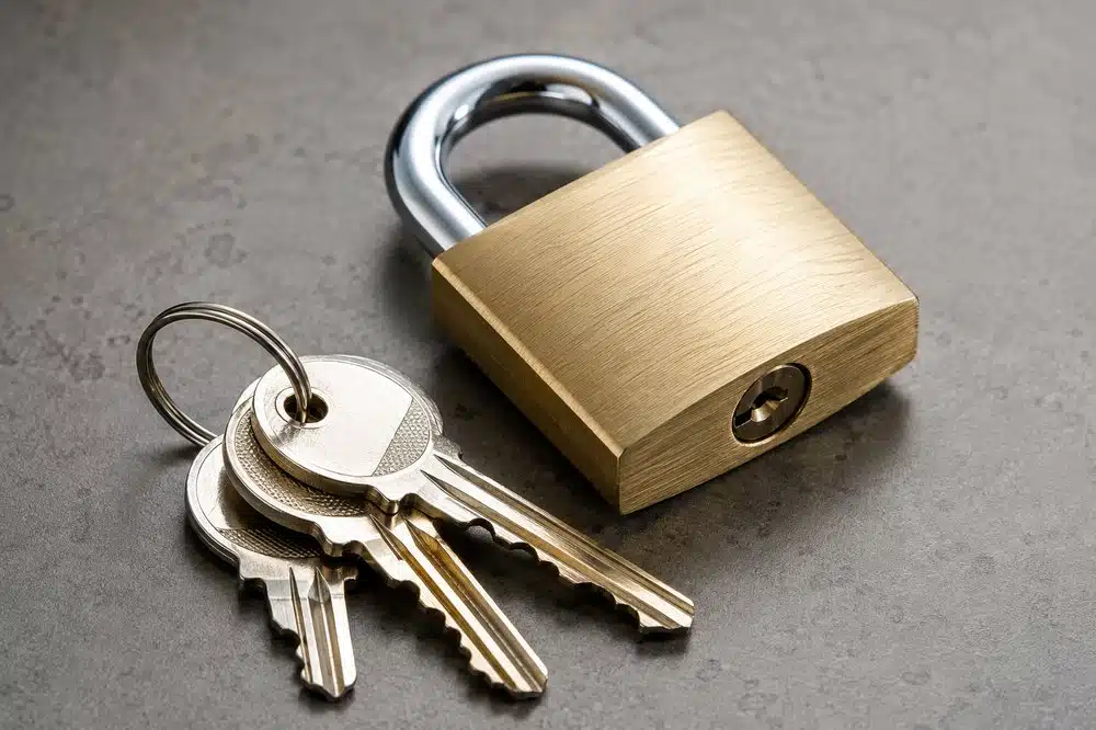 Brass padlock with set of keys on grey surface