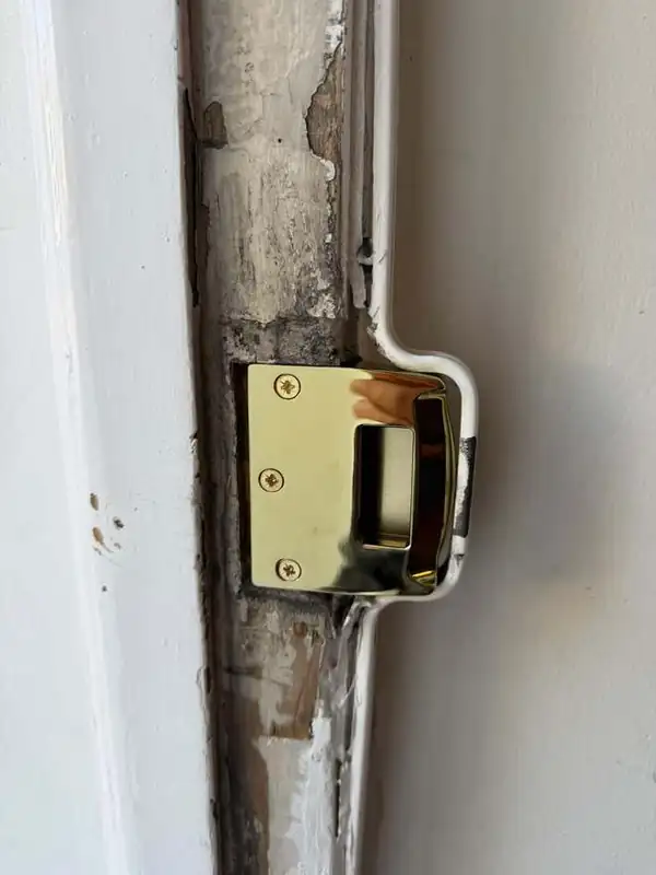 New brass night latch keep fitted to a damaged timber door frame after a break-in in Battersea
